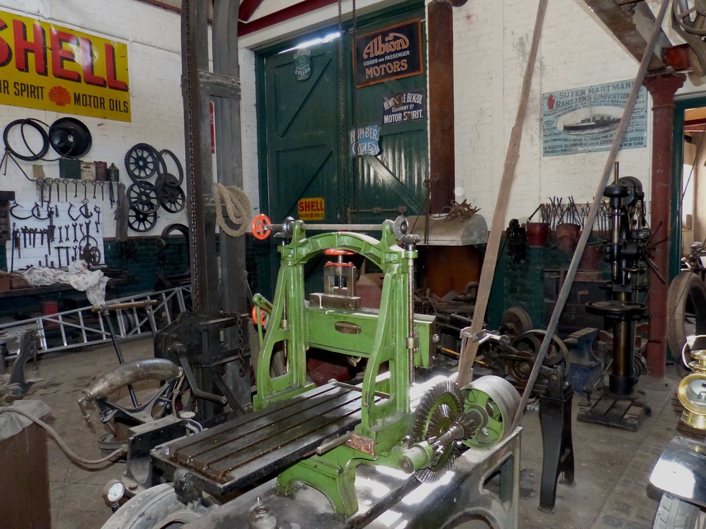 Inside an old garage workshop with a green milling machine and tools on the wall
