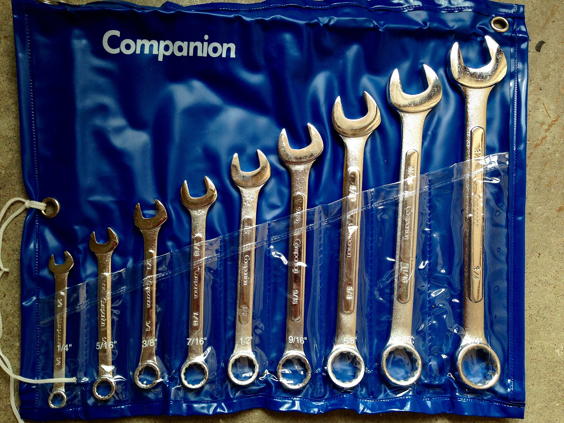 A roll of combination wrenches laid out from smallest to largest on blue vinyl